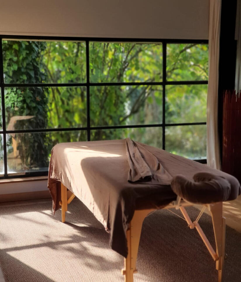 Table de massage dans un cabinet lumineux avec vue sur la nature